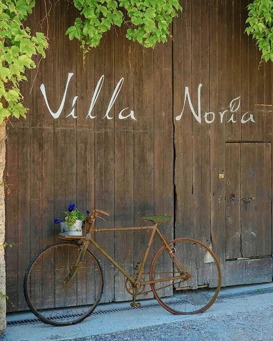 Il portone di legno di Villa Noria, con una bicicletta appoggiata