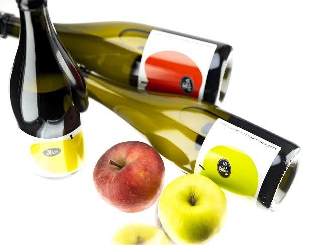 Bottiglie di sidro Pecis distese, con due mele