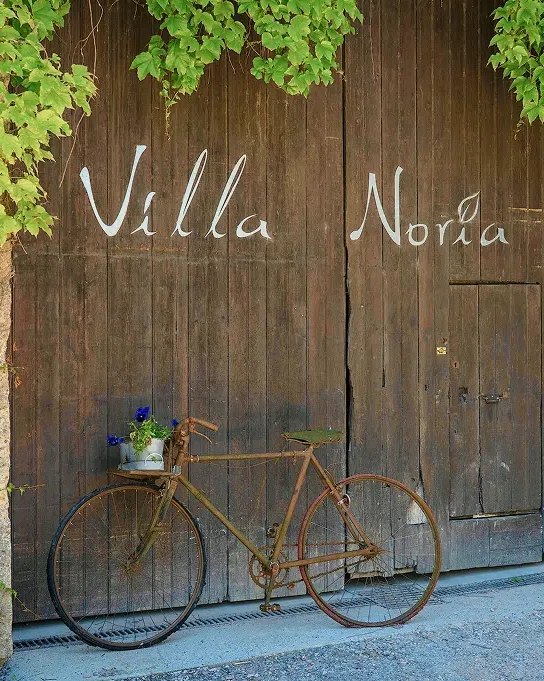 Il portone di legno di Villa Noria, con una bicicletta appoggiata